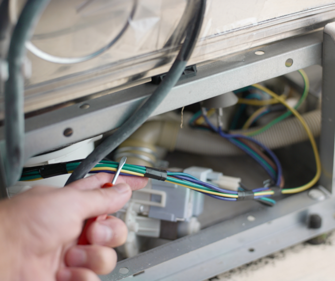 man checking wires on appliance